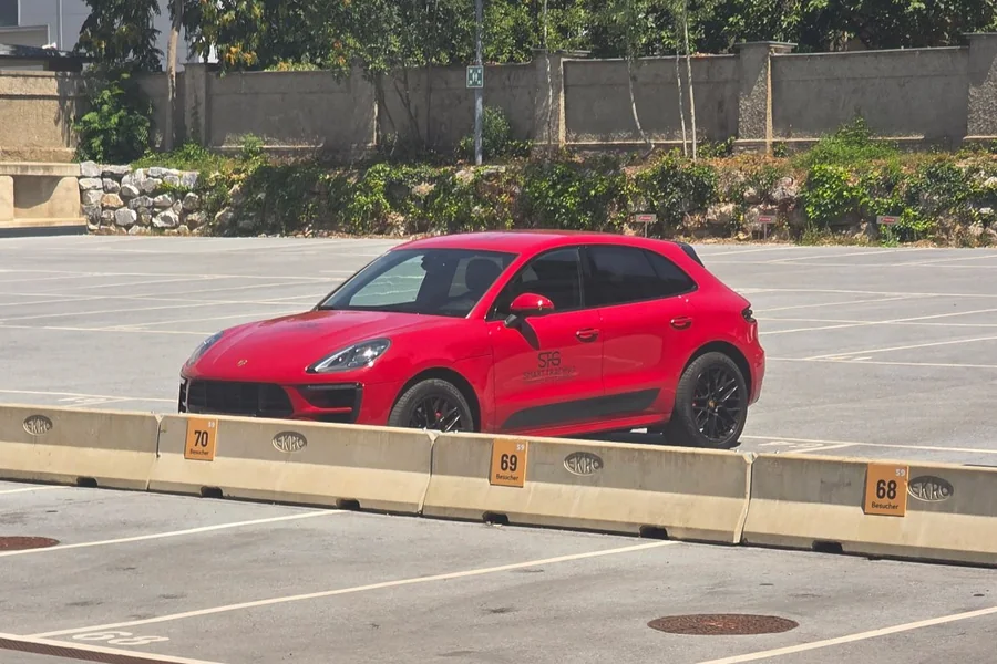 Roter Porsche mit STG-Logo auf dem Besucherparkplatz, daneben die nummerierten Stellplätze