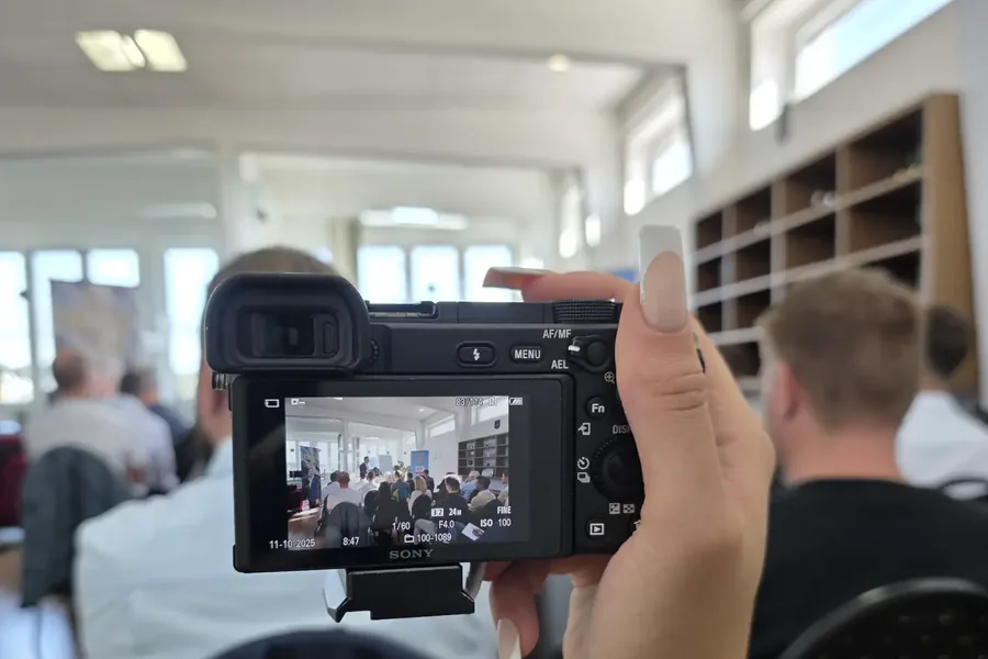 Eine Mitarbeiterin filmt den Vortrag mit