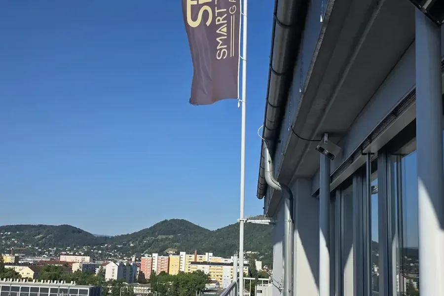 STG-Fahne vor dem Fenster, dahinter die Hügel um Graz